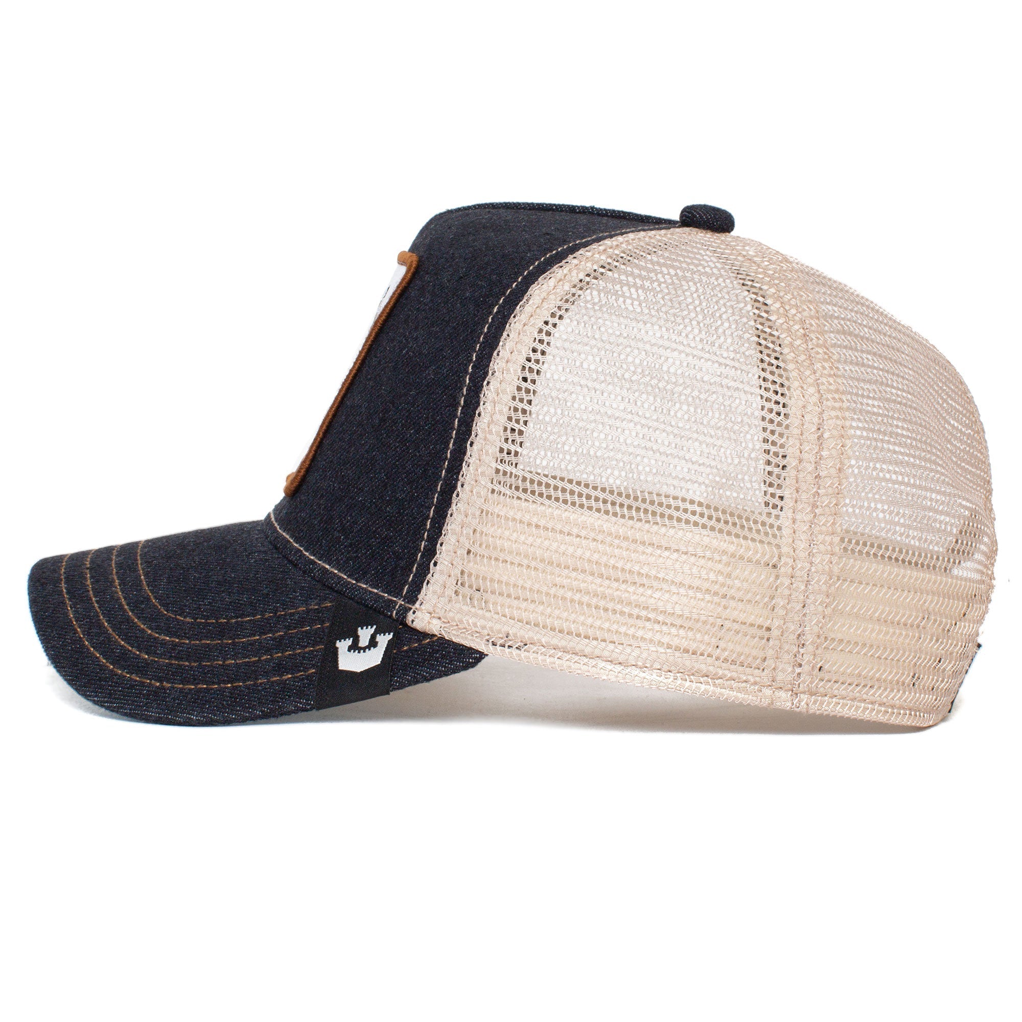 Side view of The GOAT hat—a stylish dark blue denim trucker cap with a beige mesh back and a small black tag, designed to fade over time.