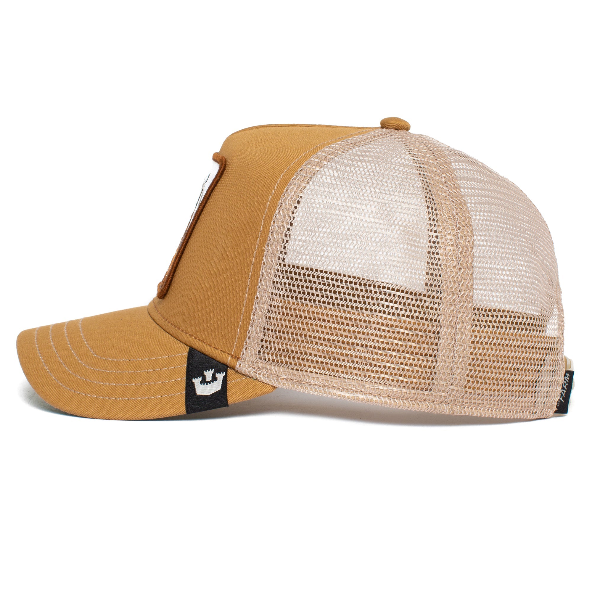Side view of The GOAT, a tan and white mesh trucker hat with a small black crown logo tag on the side, offering a timeless look that stays stylish even as the colors gently fade.